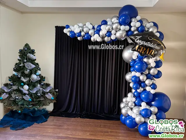 Arco orgánico de globos en azul y plateado con temática de graduación para celebrar los logros académicos de los estudiantes.