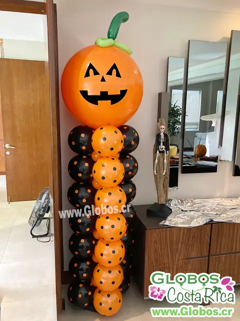 Torre de globos con calabaza sonriente para decoración de Halloween en interiores.