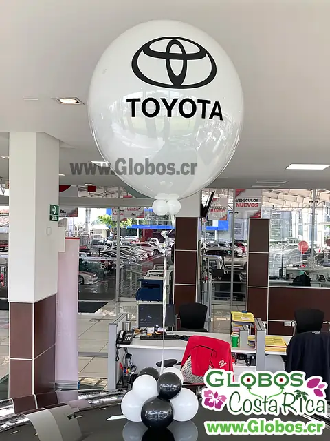 Globo decorativo blanco con el logo de Toyota en una concesionaria, destacando la marca en un entorno moderno.