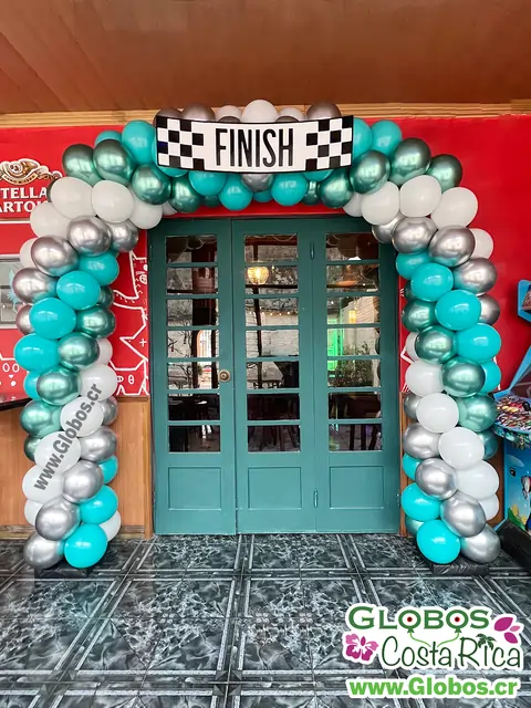 Arco de globos en tonos metálicos y blancos con temática de carrera y letrero de finish.