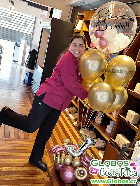 Mujer celebrando con un arreglo de globos dorados y personalizados para una ocasión especial.