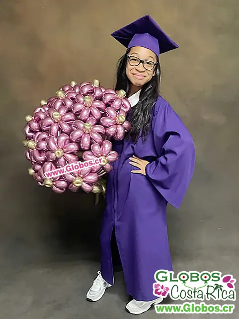 Graduada con toga morada posando con un impresionante ramo de flores de globos metálicos.