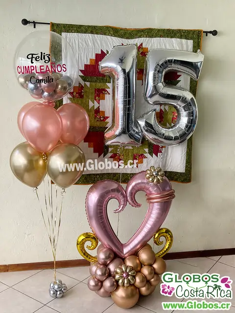 Arreglo de globos para los 15 años de Camila en tonos rosa y dorado con diseño de corazón y globos metalizados.